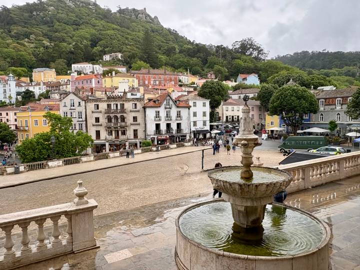 Panoramic view over Sintra’s pastel-colored buildings and a stone fountain on a cloudy day.