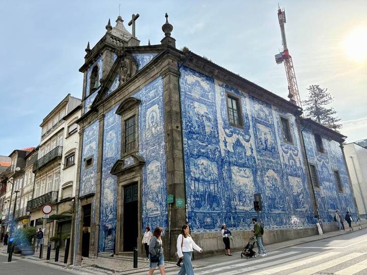The blue-tiled façade of Porto’s Chapel of Souls (Capela das Almas) with passersby on the street.