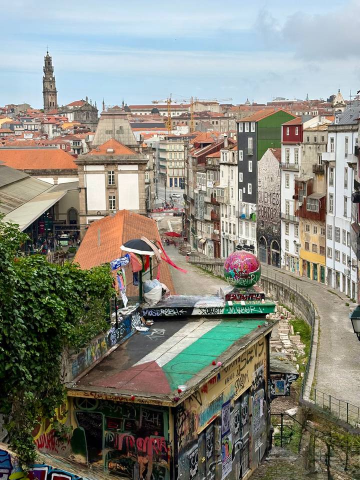 Urban view down a graffiti-decorated alley toward Porto’s historic district with colorful buildings.