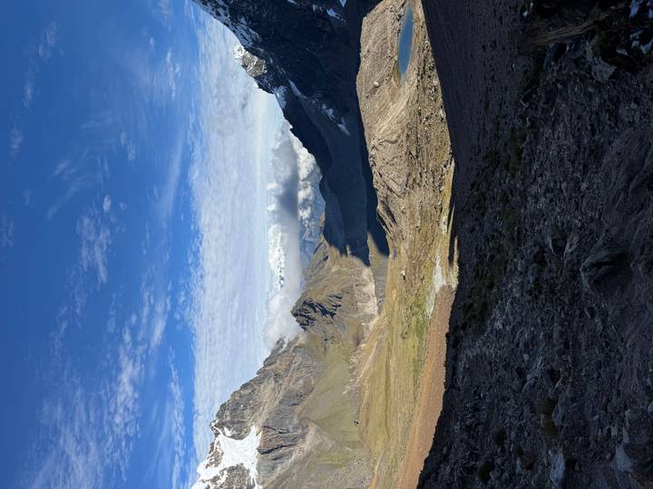 Expansive high-altitude valley with distant snowy peaks under a bright sky.