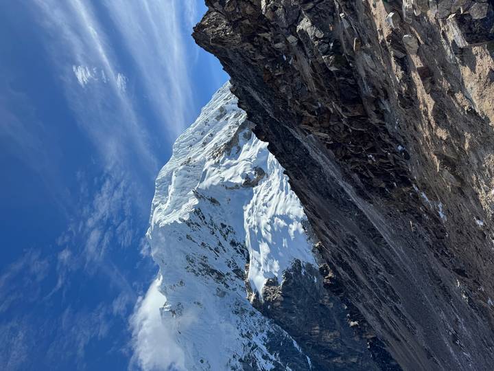 Close view of a rugged, snow-capped Andean massif under a deep blue sky.