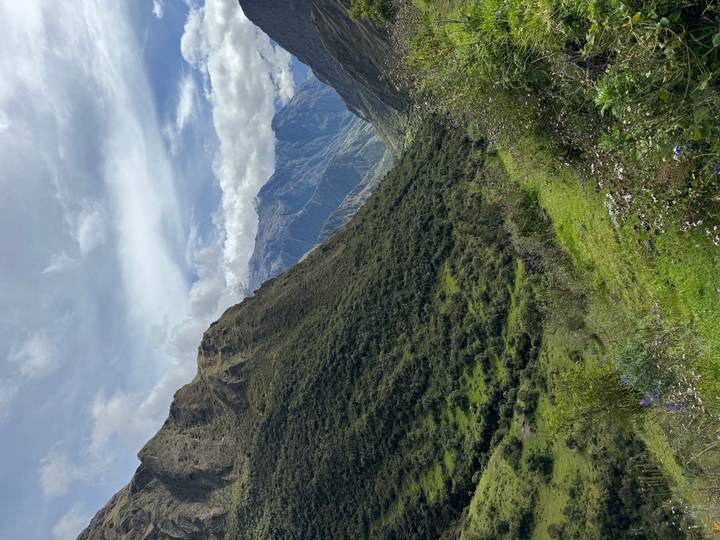 Verdant valley flanked by dramatic Andean peaks beneath a moody sky.