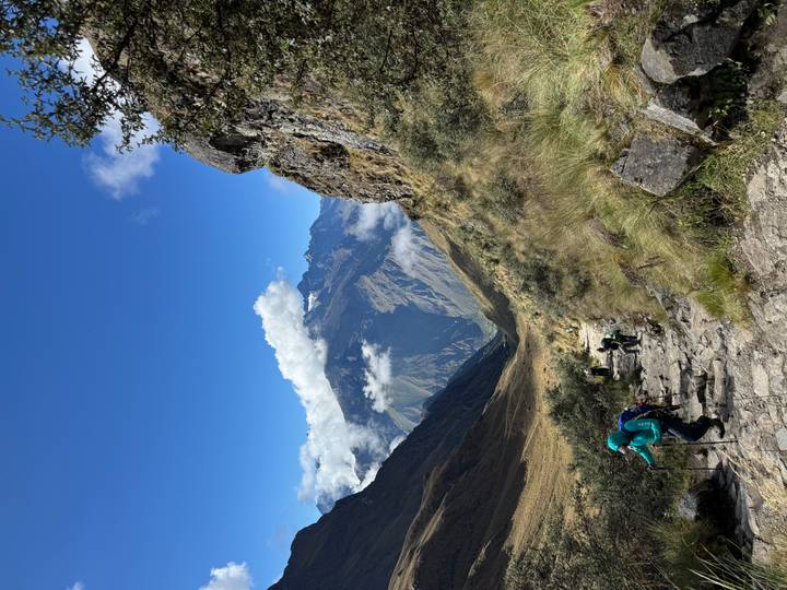 Hikers making their way up a rocky mountain path with vast peaks ahead.