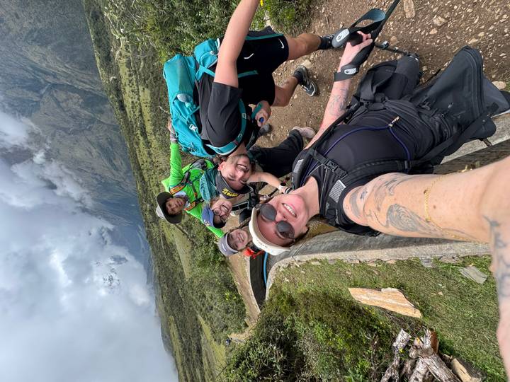 Cheerful group selfie of trekkers with misty mountains behind them.