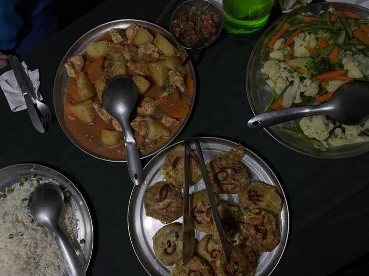 Evening meal of rice, vegetables and stew served on metal plates in camp.