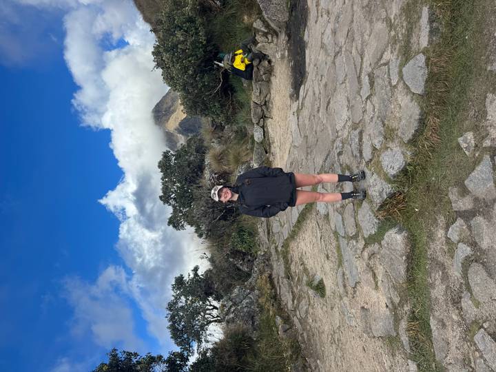 Solo traveler standing on stone paving with cloud-shrouded peak in background.