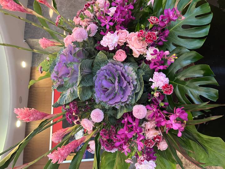 Vibrant floral arrangement featuring purple ornamental cabbage, orchids and tropical blooms.