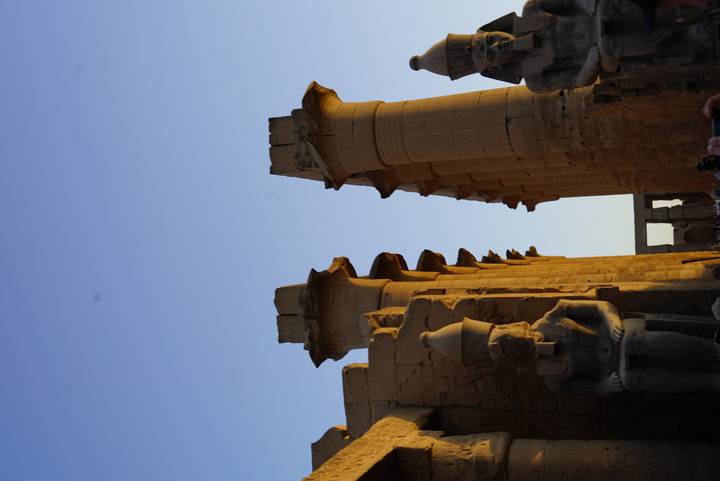 Soaring papyrus-style columns and seated statues bathed in warm evening light at Luxor Temple.