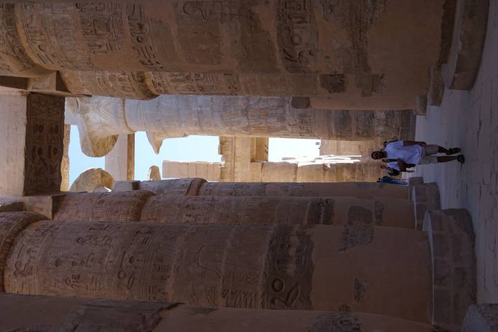 Visitor walks through the immense hieroglyph-covered columns of Karnak Temple’s hypostyle hall.