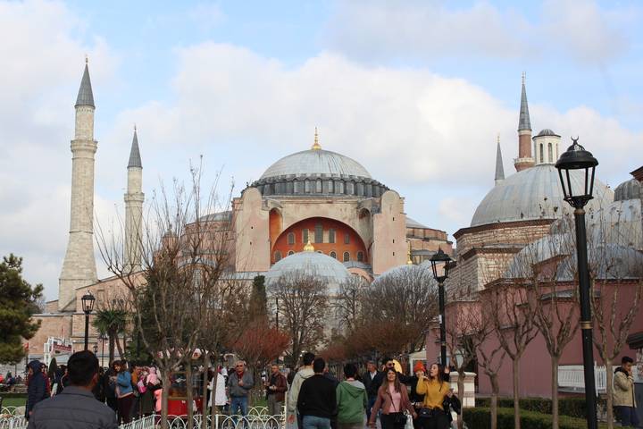 Hagia Sophia’s massive dome and minarets rise over a bustling pedestrian avenue lined with trees.