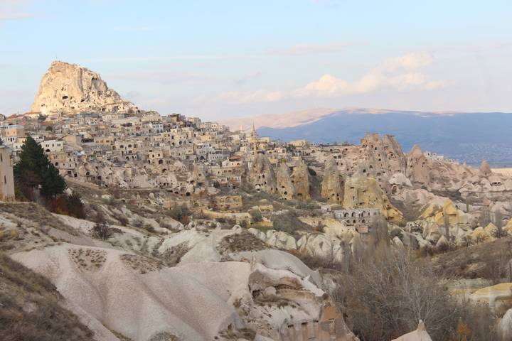 Fairy-chimney rock formations and cave dwellings sprawling across a Cappadocian hillside in soft afternoon light.