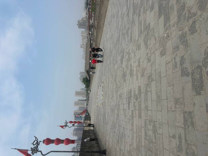 Visitors stroll along the broad stone ramparts of Xi'an's ancient city wall with modern high-rises beyond.