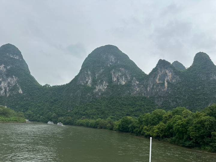 Steep karst peaks cloaked in dense forest rise sharply from a misty river in Guilin.
