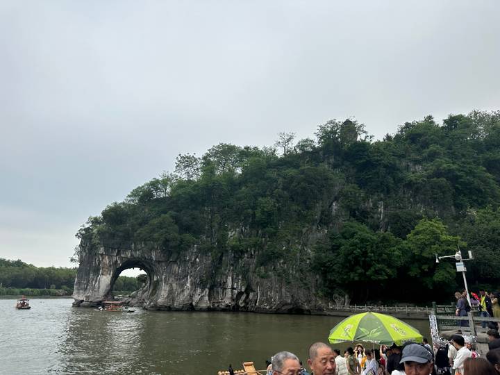 The famous Elephant Trunk Hill arches into the river beside verdant forest and tour boats in Guilin.