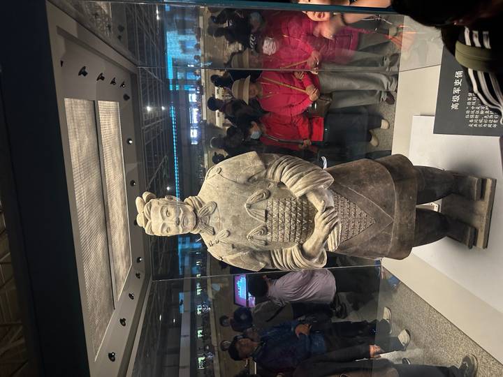 Terracotta Warrior statue displayed in a glass case with onlookers gathered around