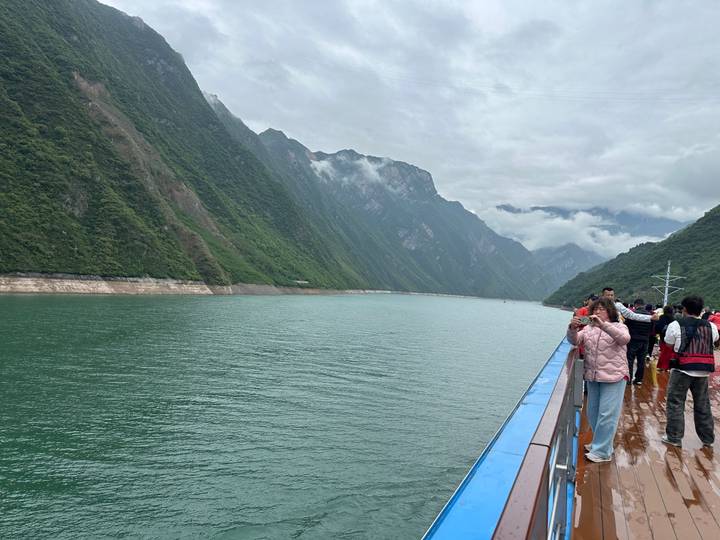 Cruise passengers enjoy views of steep green gorges along a wide turquoise river