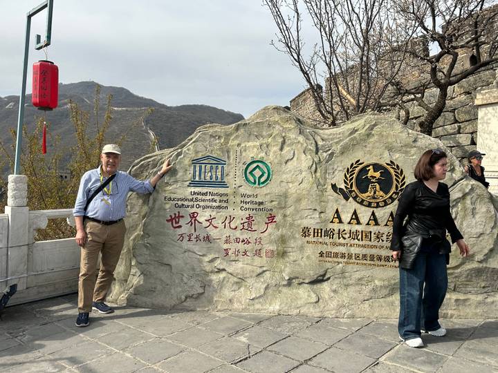 Tourist posing beside a large UNESCO world heritage stone marker at the Great Wall entrance