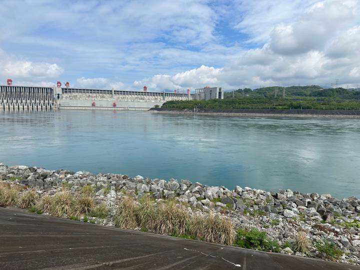 Massive dam structure spanning a wide calm river under partly cloudy skies