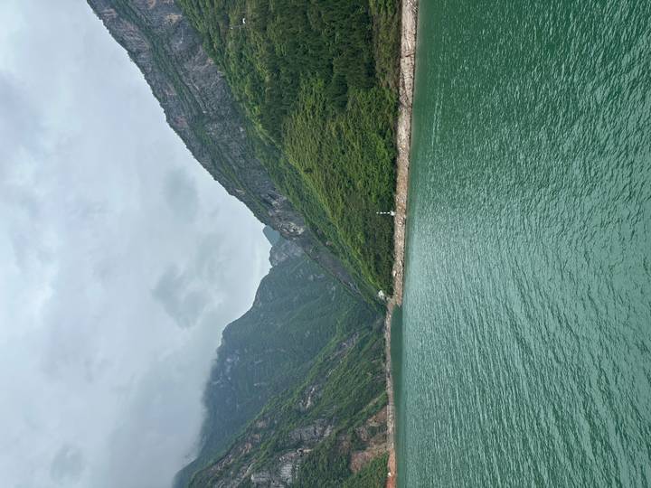 Green river winding through high mountains with a lone lighthouse on the shore
