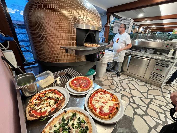 Pizzaiolo preparing authentic wood-fired pizzas in a rustic Italian pizzeria kitchen