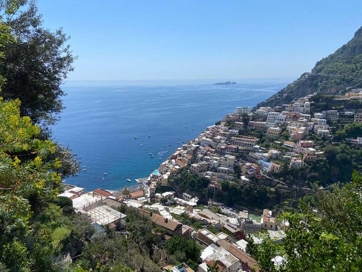 High vantage view of colorful Positano cascading down steep cliffs to the blue Tyrrhenian Sea dotted with boats