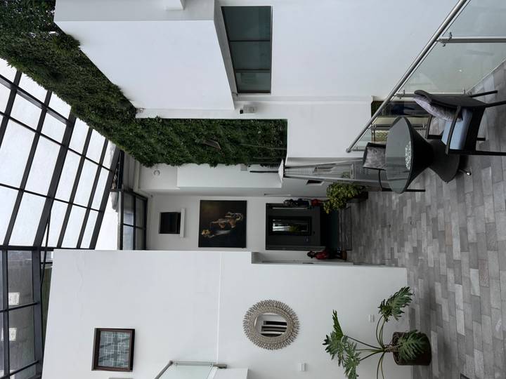 Modern boutique hotel atrium with glass roof, vertical garden wall and minimalist furnishings.