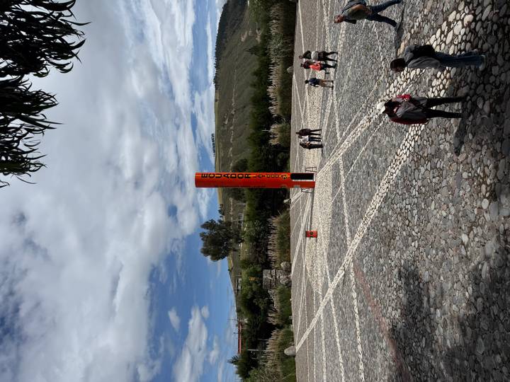 Open plaza at the Mitad del Mundo monument with visitors standing on the equatorial line.