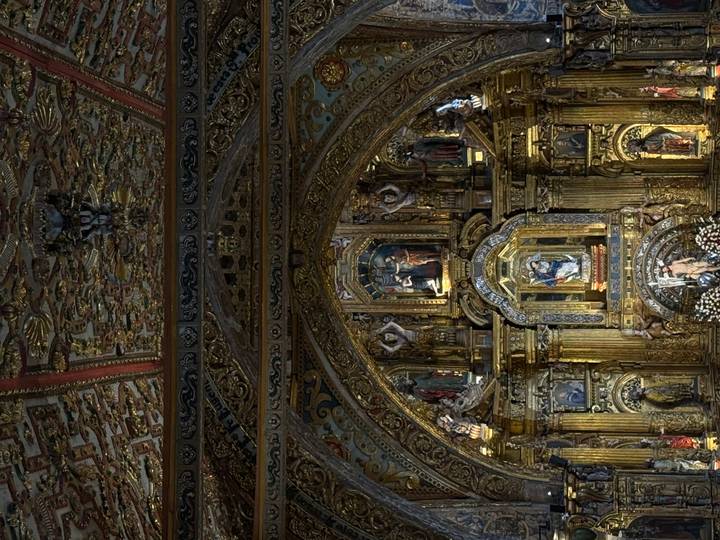 Lavish baroque altar covered in gold leaf and religious statues inside an ornate church.