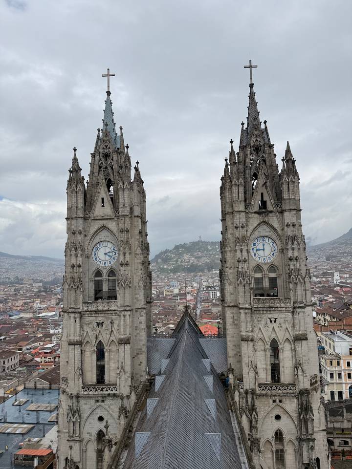 Twin clock towers of a neo-Gothic basilica rise above the cityscape panorama.