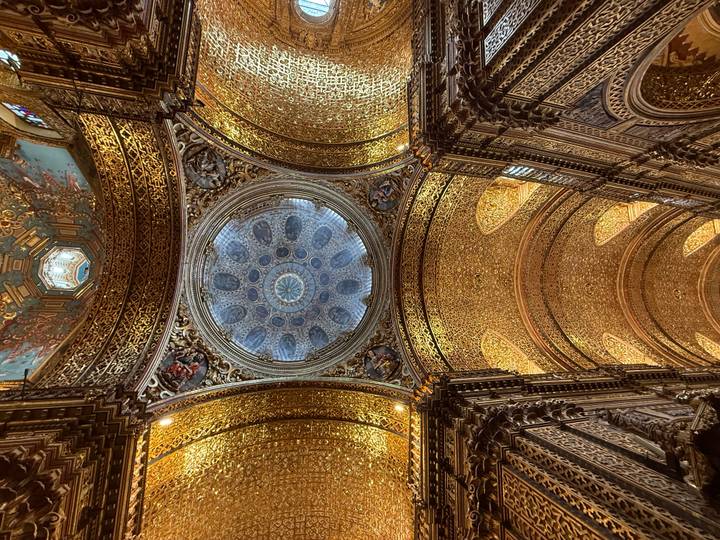 Golden ornate church ceiling with a blue starry dome centerpiece framed by intricate carvings.
