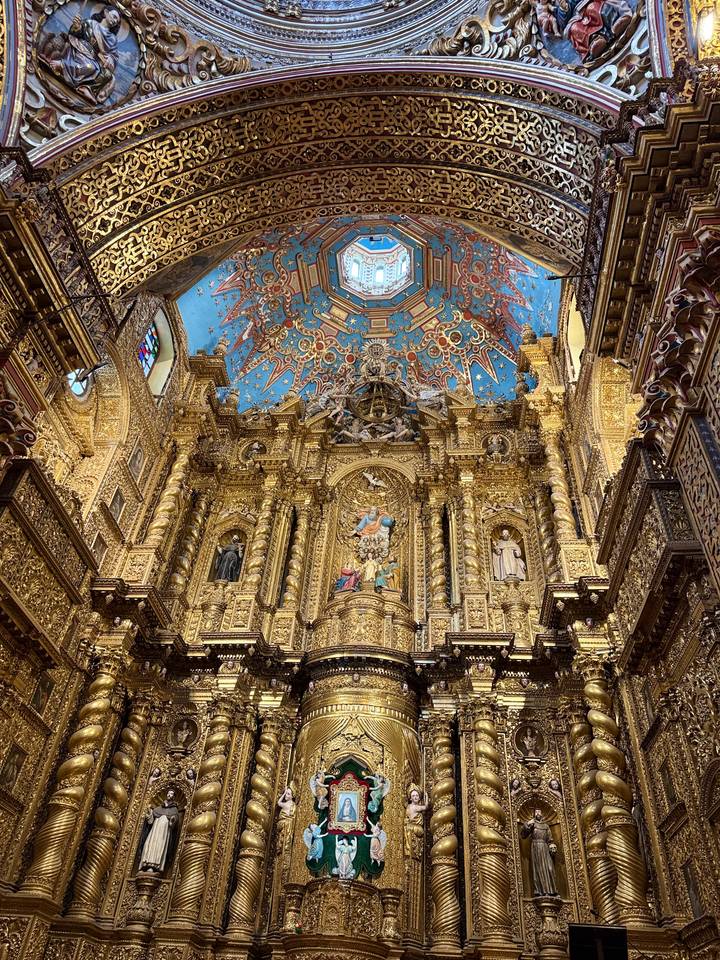 Magnificent gilded altar with vivid blue ceiling painted with stars inside an ornate church.