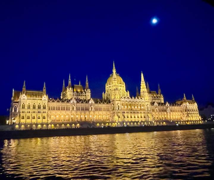 Dramatically lit Hungarian Parliament Building reflecting on the Danube River at night.