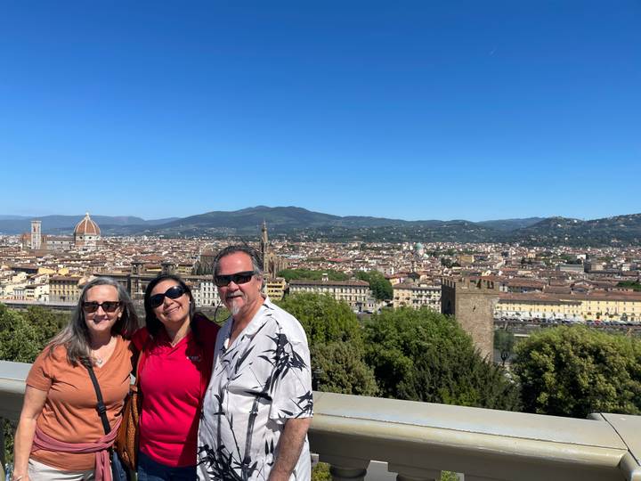 Three travelers with panoramic view over Florence including the cathedral dome and rooftops.