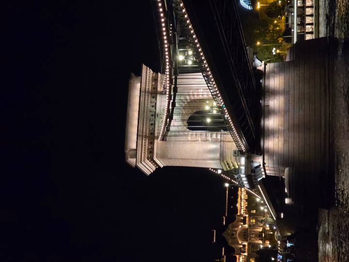 Dramatic night shot of Budapest’s Chain Bridge lit by strings of lights reflecting on the Danube.