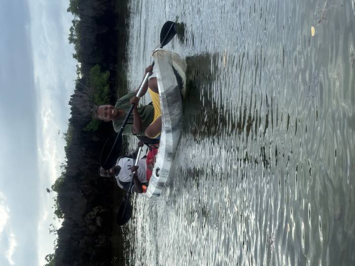 Two smiling kayakers paddling together on calm water with mangrove trees behind