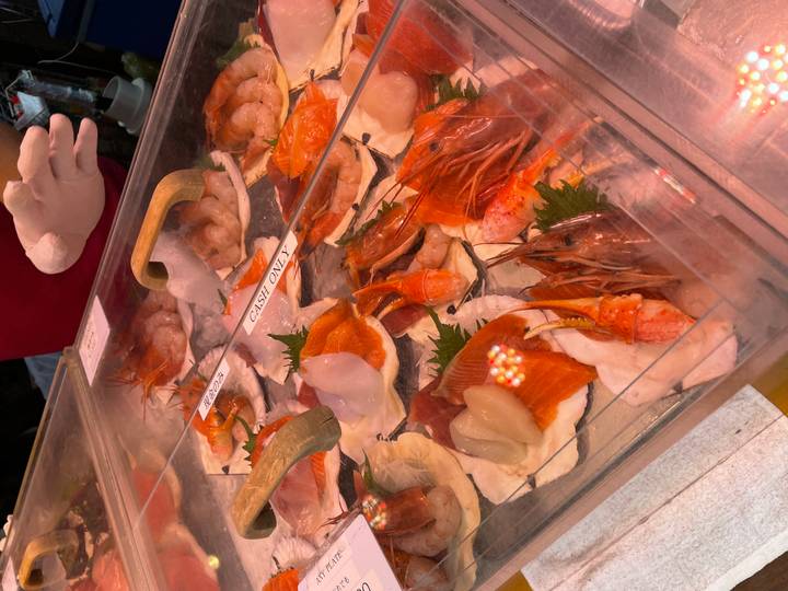 Display of fresh sashimi and prawns on ice at a Japanese seafood market stall