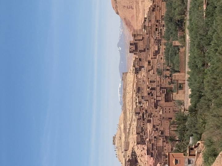 View over adobe kasbah village with snow-capped Atlas Mountains on horizon