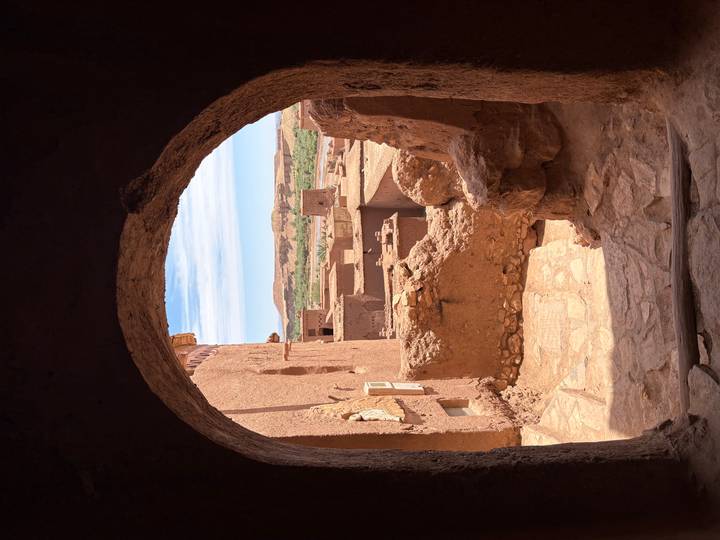 View through stone arch to mud-brick kasbahs and desert landscape beyond