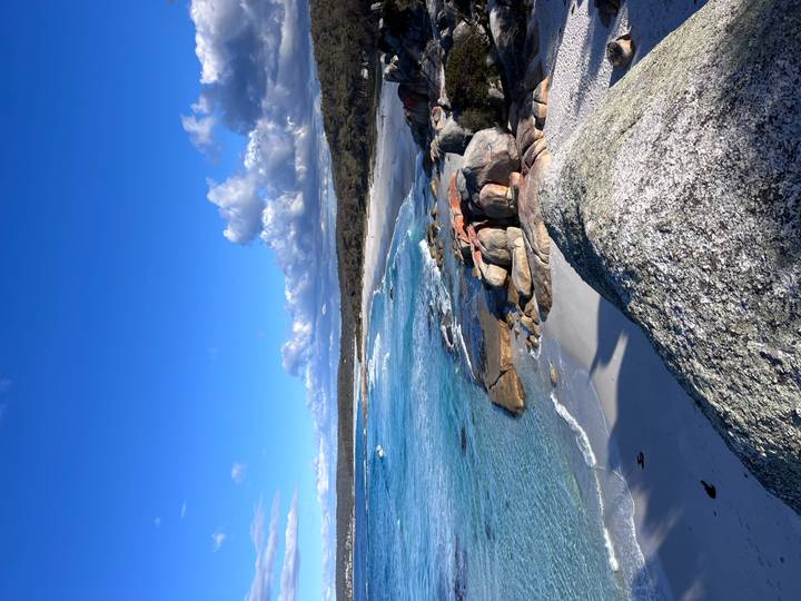 Pristine white-sand beach, granite boulders and vibrant turquoise water under a deep blue sky.