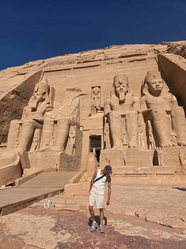 The colossal seated statues of Abu Simbel dominate the sandstone facade under bright sun.
