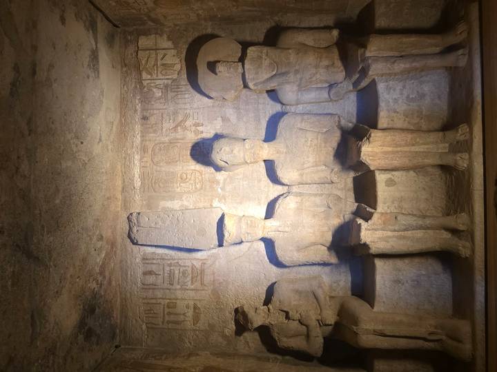 Four seated stone gods are softly lit within the inner sanctuary of Abu Simbel.