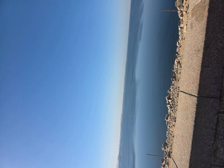 A tranquil expanse of blue water stretches to the horizon beneath a cloudless sky.