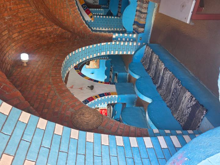 Colourful interior of a Nubian-style restaurant or cafe with blue benches, arched brick ceilings and decorative tiles.