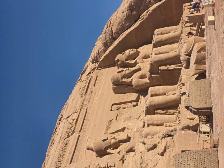 Wide-angle view of the Great Temple at Abu Simbel with colossal seated statues carved into sandstone cliff.