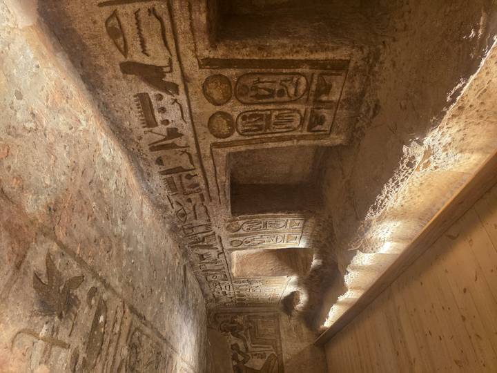 Narrow chamber with hieroglyphic walls and illuminated niches in an Egyptian tomb.