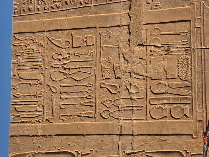 Close-up of crisp hieroglyphic inscription carved in sandstone block under warm light.