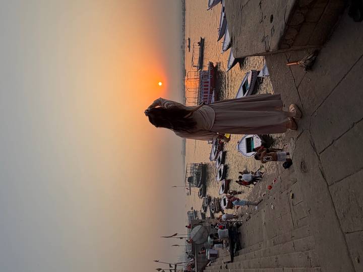 Silhouetted woman watches the sun set over boats on the Ganges at Varanasi’s ghats.