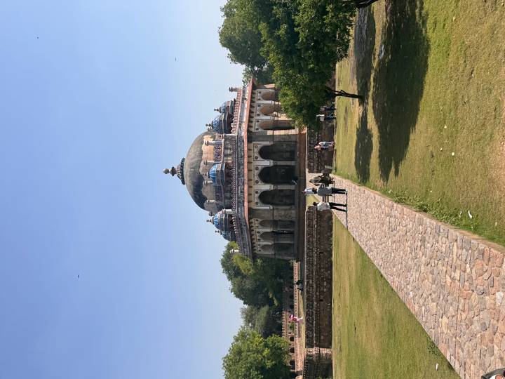Domed Isa Khan’s Tomb stands at the end of a stone path amid green lawns in Delhi.