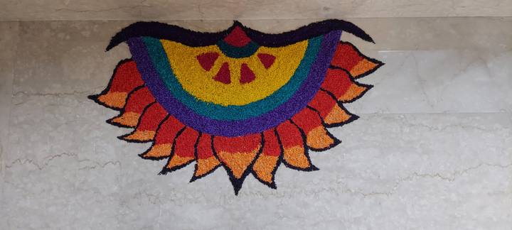 Colorful flower-shaped rangoli art created with powdered pigments on marble floor
