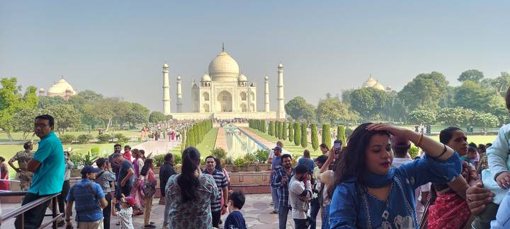 Crowded viewing area in front of the Taj Mahal with visitors taking photos